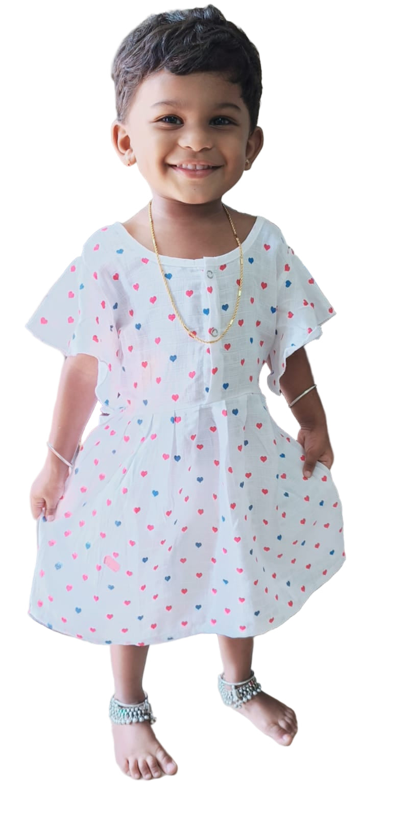 Child wearing a white dress with colorful polka dots indoors.