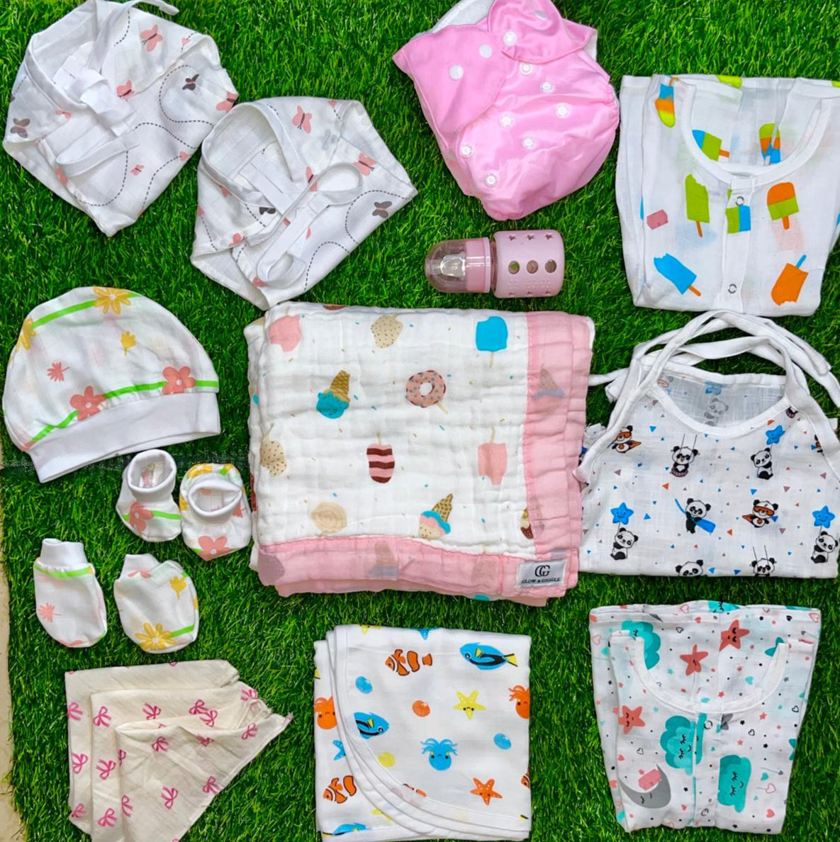 Collection of baby clothes and items on a grass-like surface
