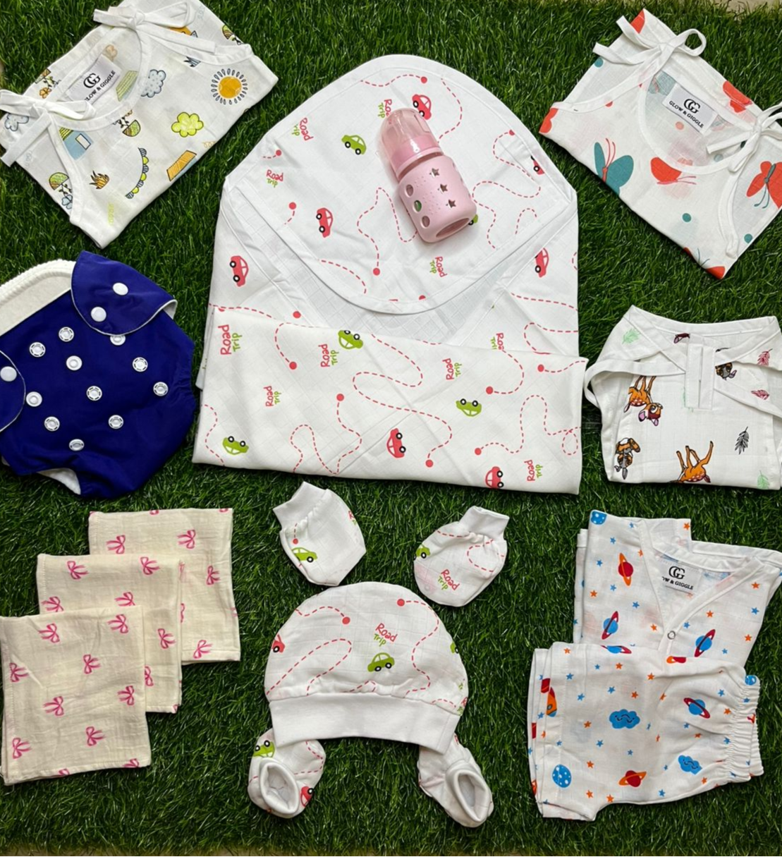 Collection of baby clothes and accessories on a grass-like surface