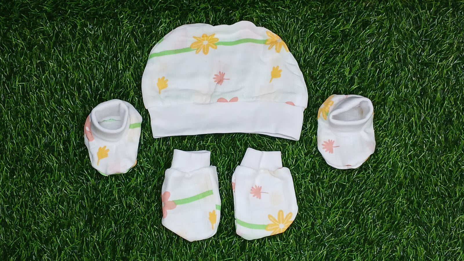 Baby clothing set including a hat, socks, and pants on grass